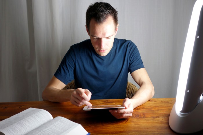 Man reading while using light therapy box