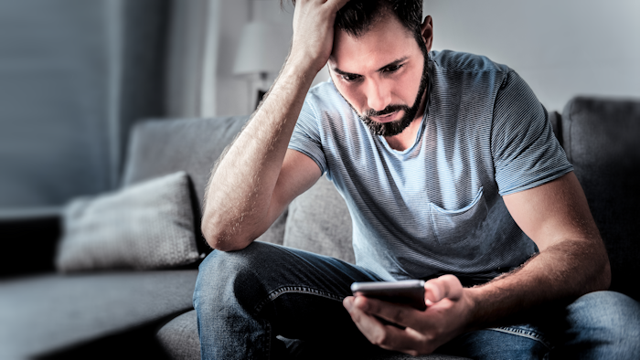 Distraught man looking at his phone